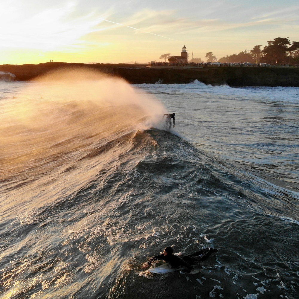 Surfer catching a wave at sunset along the scenic Santa Cruz coast in California.