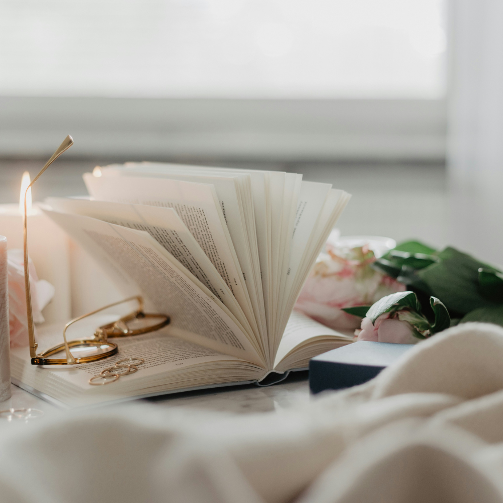 Cozy reading nook with a soft throw blanket, open book, lit candle, and warm cup of tea creating a peaceful space for a relaxing Quiet Hour at home.